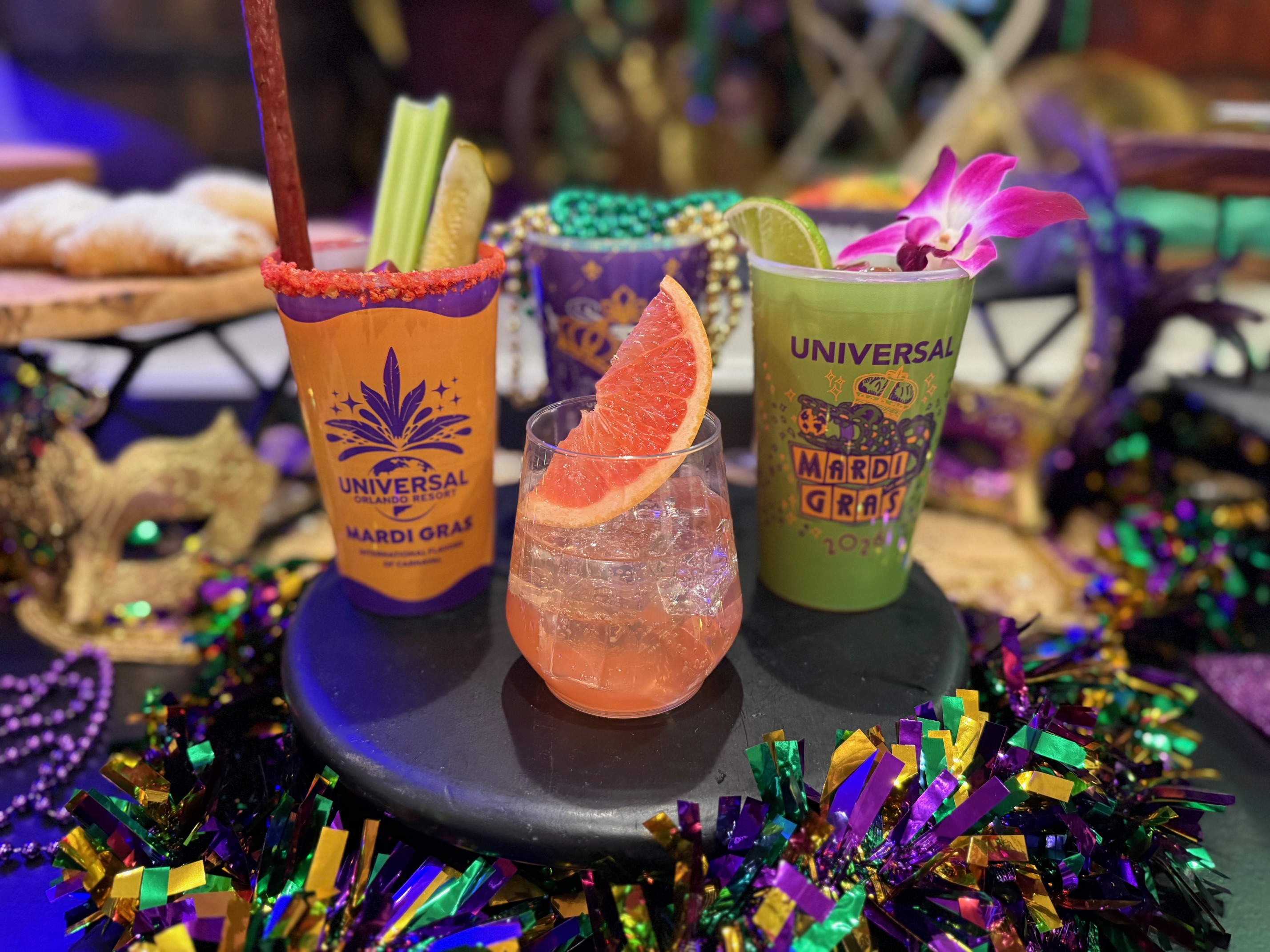 three Universal Orlando Mardi Gras cocktails with colorful decorations