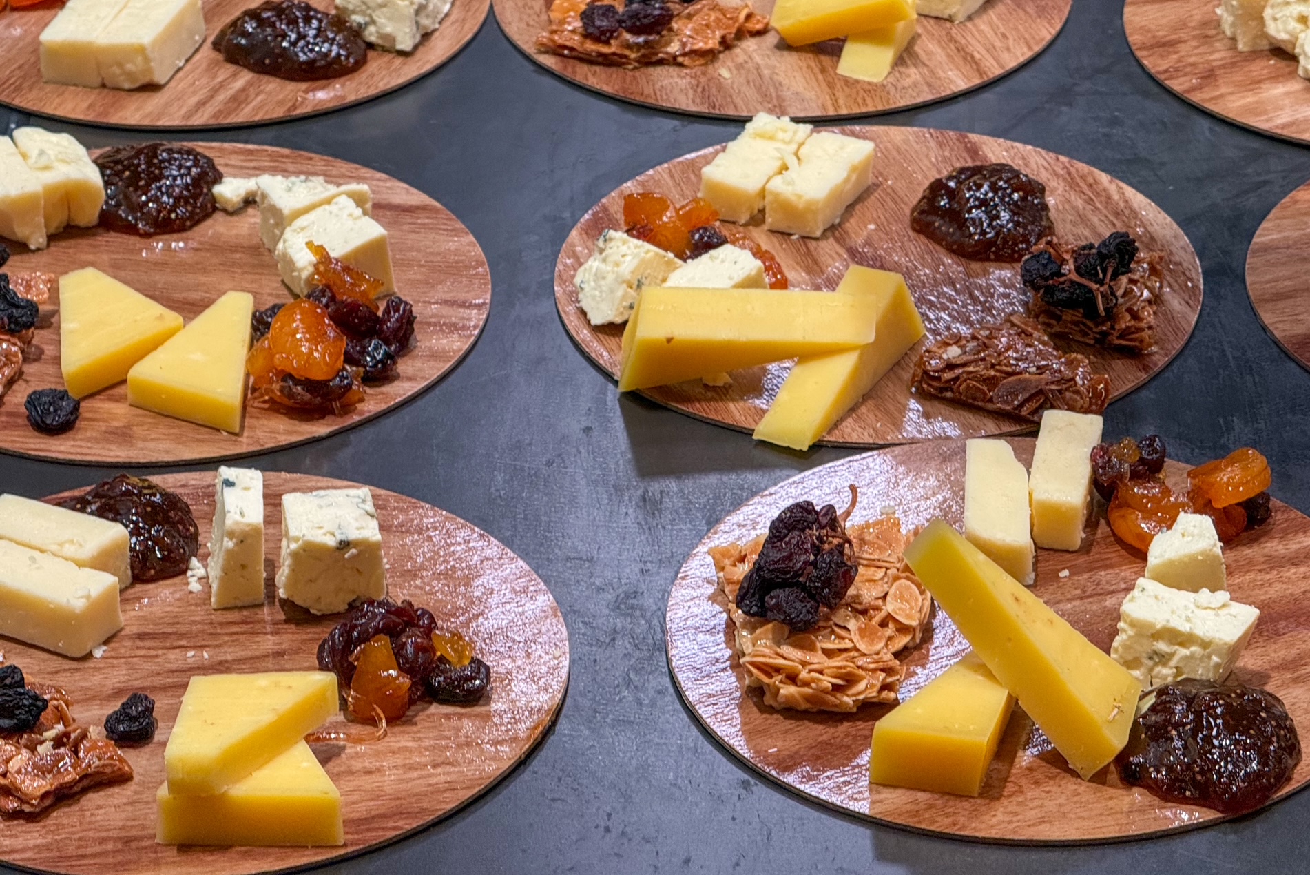 multiple small cheese plates with cheese and dried fruit