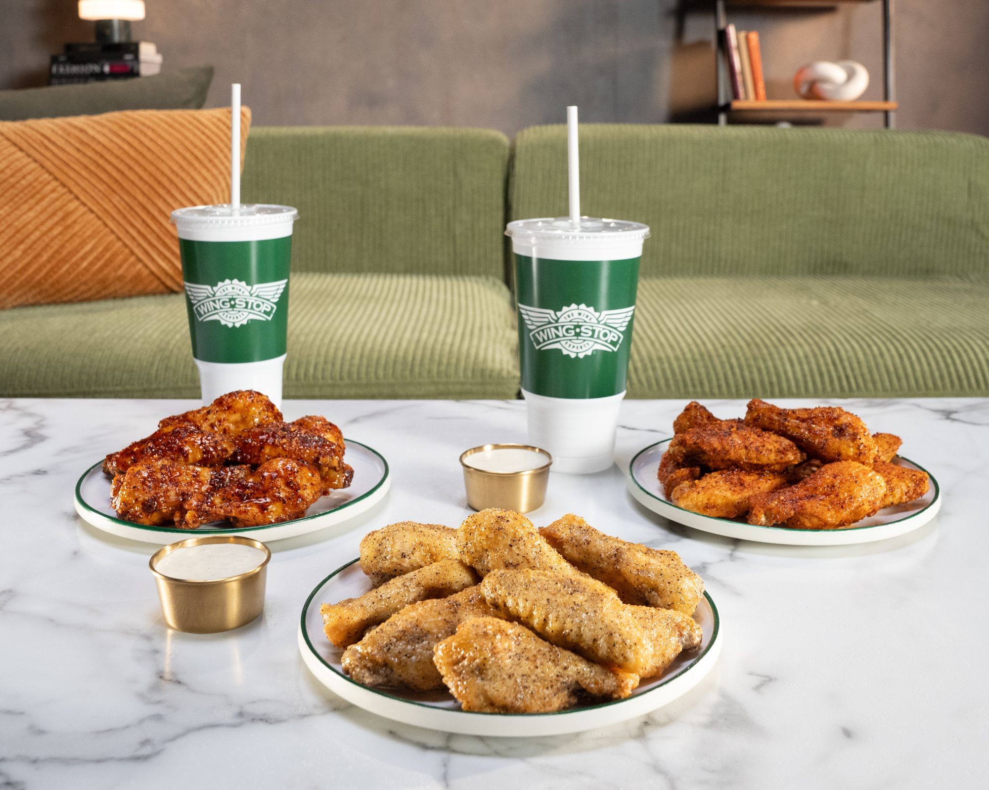 three plates of Wingstop chicken wings with two drinks
