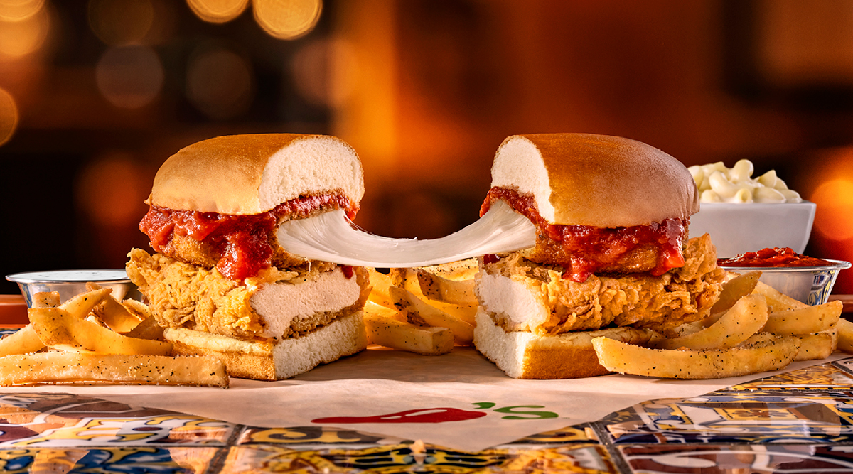 chicken parm sandwich with long cheese pull on a plate with fries
